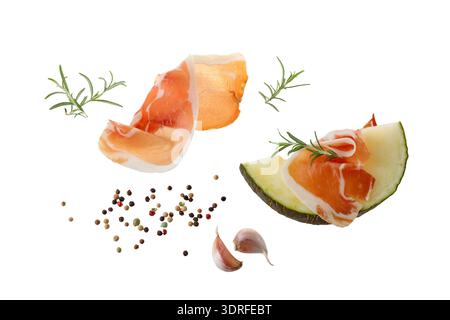 Traditional spanish jamon slices (dried pork meat) with melon and fresh herbs  flying isolated on white background Stock Photo