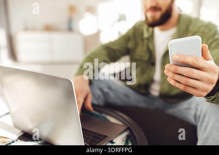 Unrecognizable Man Using Smartphone And Laptop Indoors, Cropped Shot Stock Photo