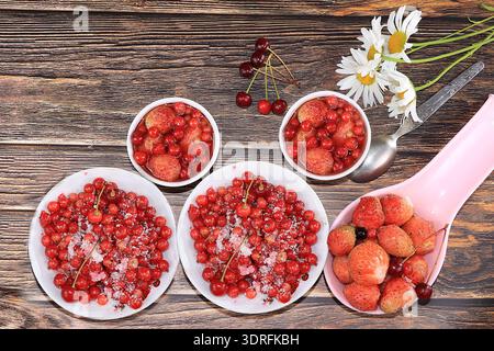 Summer berries of currants and strawberries on a wooden table, top view. Natural berries of currants and strawberries and jam fr Stock Photo
