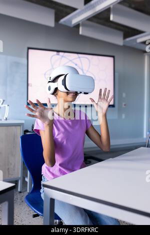 Using VR headset, student in school classroom experiencing virtual reality Stock Photo