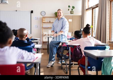 Engaging with diverse students, female teacher fostering interactive learning in classroom at school Stock Photo