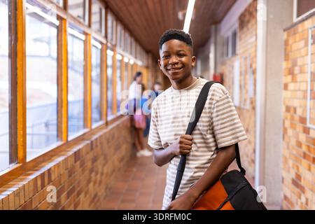 Smiling student in school hallway carrying bag, ready for class Stock Photo