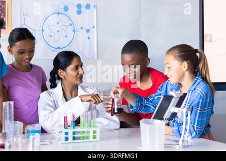 In school, Indian female teacher and students conducting science experiment with test tubes Stock Photo