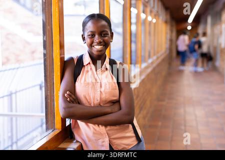 Smiling student standing in school hallway with backpack, feeling confident Stock Photo