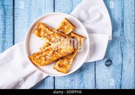 Close up of appetizing croutons in powdered sugar on a plate on the table top view Stock Photo