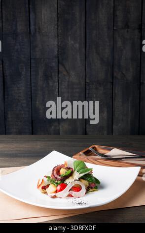 New Dish Featuring Octopus Served on a White Plate in a Simple Restaurant Setting Stock Photo