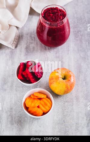 Beetroot, carrot and apple pieces in bowls for making ABC juice on the table vertical view Stock Photo