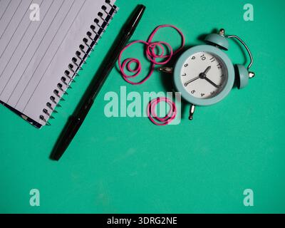 Notepad and alarm clock on green background Stock Photo