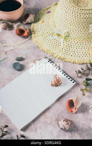 Notebook, beach hat, shells and stones on the table vertical view Stock Photo