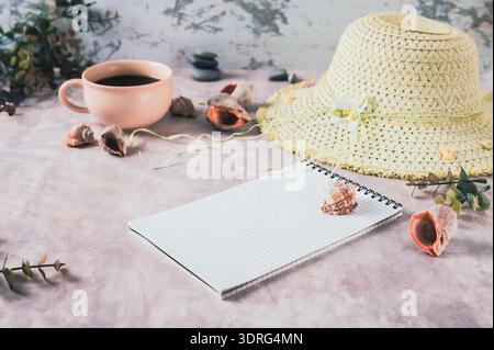 Notebook, beach hat, shells and stones on the table Stock Photo