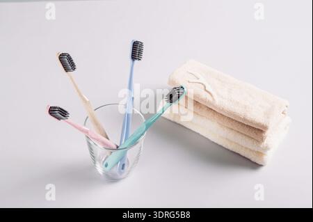 Toothbrushes in a transparent glass and a stack of towels on a gray background Stock Photo