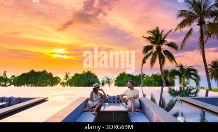 Couple enjoying a romantic sunset in an infinity pool at a luxury resort in Thailand Stock Photo