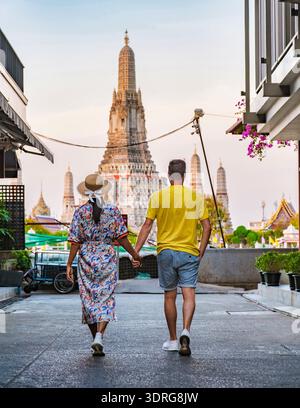 Couple enjoys a romantic stroll hand in hand towards Wat Arun at sunset in Bangkok Stock Photo