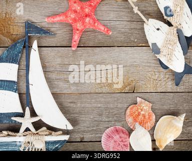 Toy sailboat and fish with seashells and starfish on a wooden background Stock Photo
