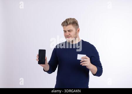 Man in blue sweater holding a smartphone and credit card Stock Photo