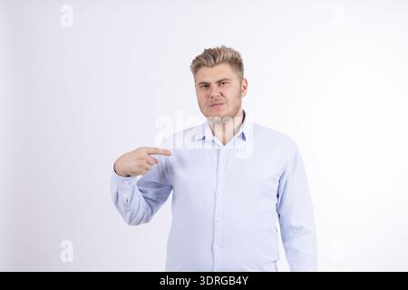 Young man in blue shirt pointing finger at himself Stock Photo