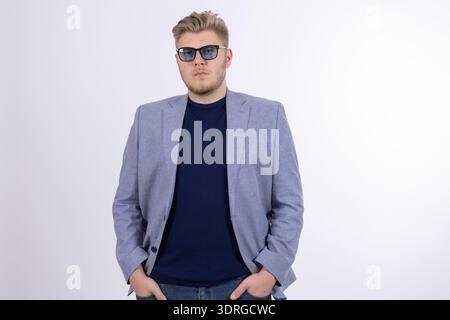 Confident man in blue jacket posing with hands in pockets Stock Photo