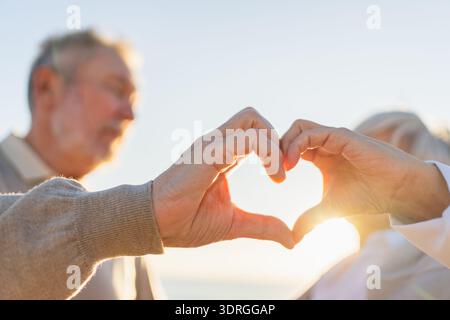 Love heart shape peace. Senior older couple making heart shape with their hands. Adult mature old husband wife showing heart sig Stock Photo