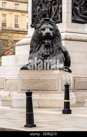 Bronze lion on a plinth at the base of Nelson's Column in Trafalgar Square, London, UK Stock Photo