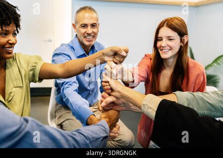 Business people stacking fists celebrating teamwork success Stock Photo
