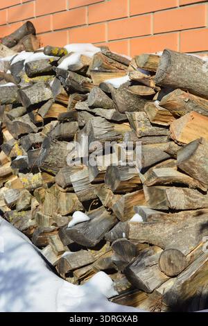Stacked firewood covered in snow Stock Photo