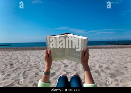 Woman reading a book on the beach Stock Photo