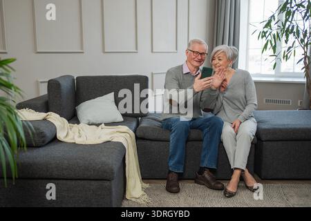 Video call. Happy senior couple woman man with smartphone having video call. Mature old grandmother grandfather talking speaking Stock Photo