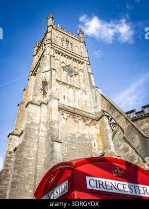 Low angle view of a historic stone cirencester abbey tower and vibrant red classic telephone box in Cirencester Stock Photo