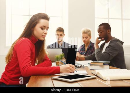 Students Engaged in Study Session With Digital Devices and Books Stock Photo