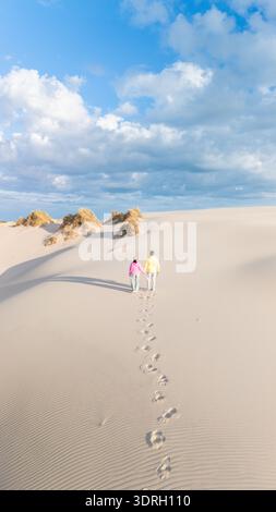 Couple strolling on sandy dunes under a bright blue sky in Denmark Stock Photo