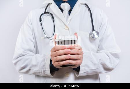 Hands of doctor holding takeaway coffee on isolated background. Doctor hands holding paper coffee Stock Photo