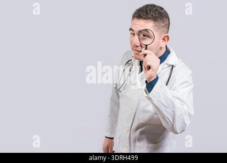 Doctor holding magnifying glass and looking at camera on isolated background. Doctor with magnifying glass looking at the camera Stock Photo