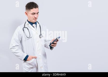 Young latin doctor holding telephone isolated. Handsome doctor using phone on isolated background. Stock Photo