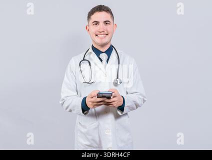Happy latin doctor holding phone isolated. Cheerful doctor using cellphone looking at camera isolated. Stock Photo