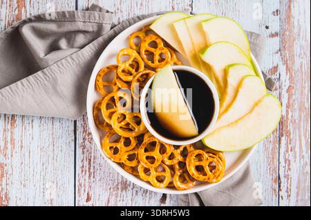 Close up of miso caramel dipping sauce, granny smith apples and pretzels on a plate top view Stock Photo