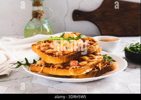 Baked toasts with bacon, cheese and tomato sauce on a plate on the table Stock Photo