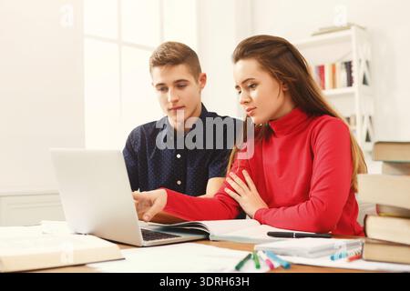 Students Study Together in a Cozy Space While Using a Laptop and Taking Notes on a Project Stock Photo