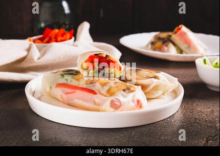 Vegetarian spring rolls with cucumber, pepper and fried mushrooms on a plate on the table Stock Photo