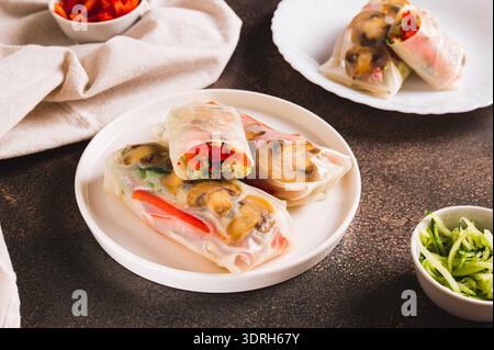 Delicious spring rolls with vegetables and mushrooms in rice paper on a plate on the table Stock Photo