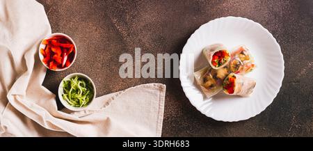 Delicious spring rolls with vegetables and mushrooms in rice paper on a plate top view web banner Stock Photo