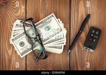 Money, glasses and car key on wooden table. View from above Stock Photo