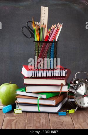 School and office supplies on classroom table in front of blackboard Stock Photo