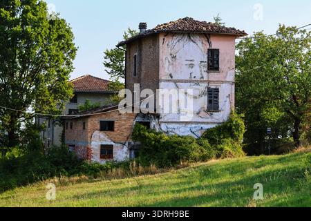 Large scale black and white portrait mural covering the facade of an abandoned rural building in Northern Italy featuring weathered brick walls and a Stock Photo