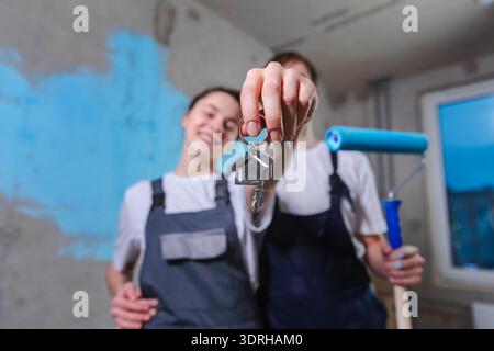 Own home. Mortgage relocation concept. Happy couple holding key from new first house. Family celebrating moving day. Husband wif Stock Photo