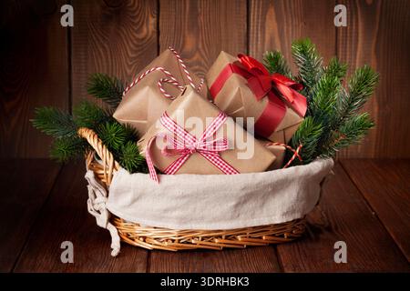 Christmas gift boxes and fir tree branch in basket on wooden table Stock Photo