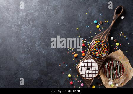 Colorful donuts and candies on stone table. Top view with copy space Stock Photo