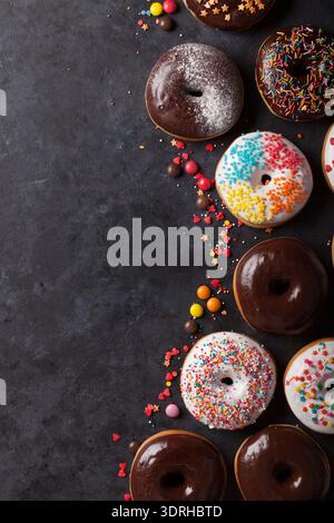 Colorful donuts on stone table. Top view with copy space Stock Photo