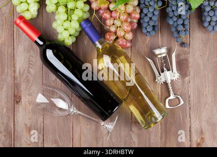 Bunch of grapes and wine bottles on wooden table background. Top view Stock Photo