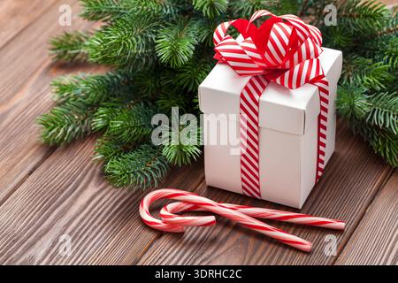 Christmas gift box, candy cane and fir tree branch on wooden table Stock Photo