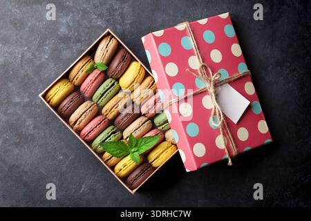 Colorful macaroons in a gift box on stone table. Sweet macarons. Top view Stock Photo